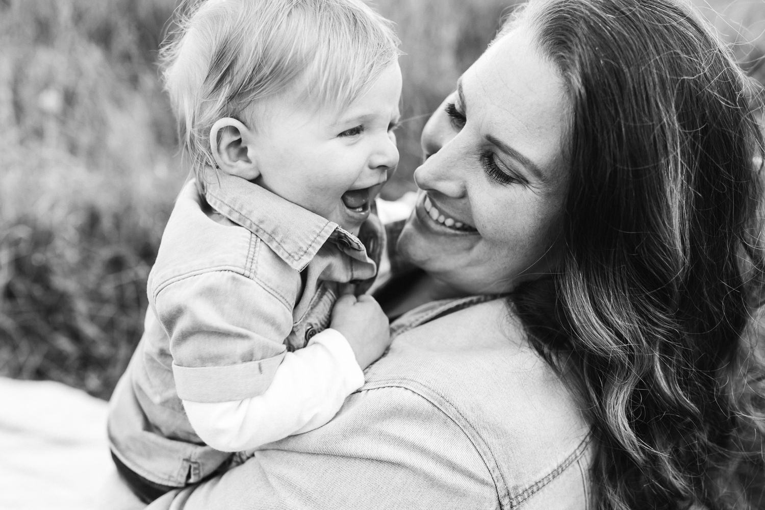 A mother and son look at each other smiling. Black and white photo.